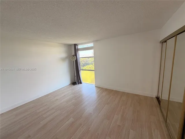 a view of empty room with a window and wooden floor