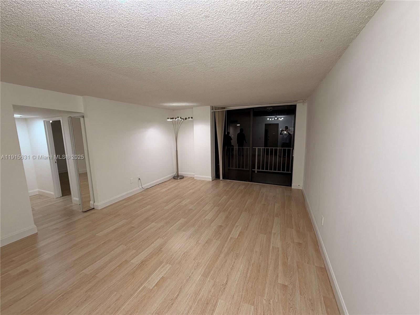 2350 Northeast 135th Street, Unit 503 North Miami, FL 33181 - Photo 3 of 9 an empty room with wooden floor and mirror