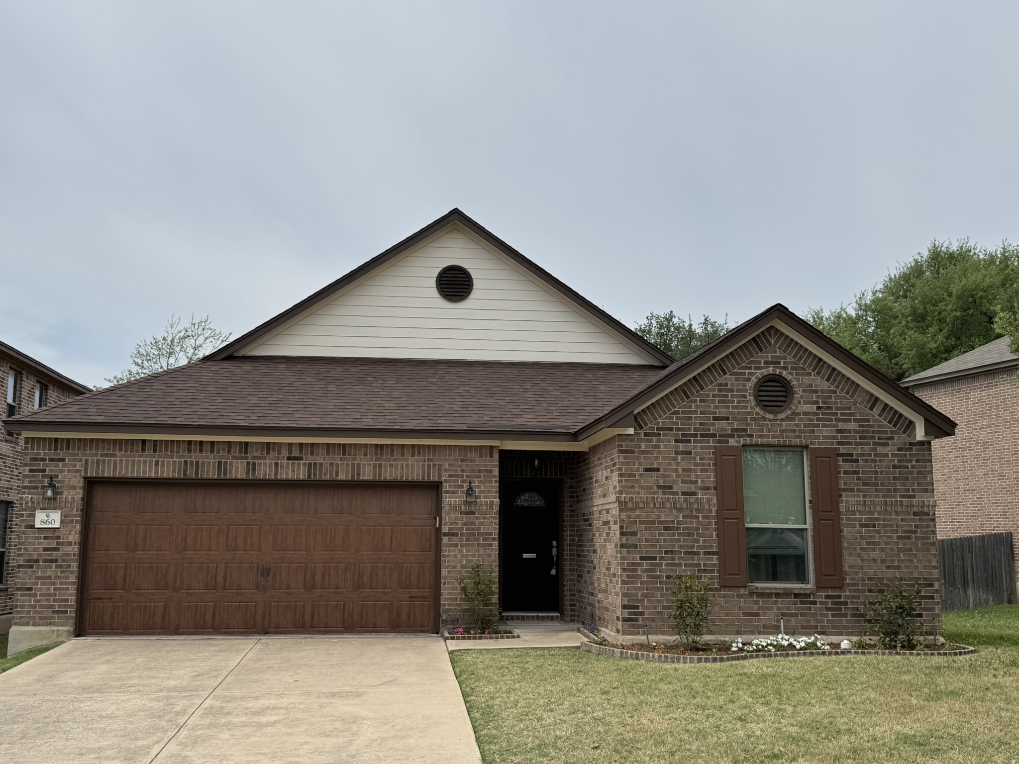 Ranch-style home with an attached garage, concrete driveway, brick siding, a shingled roof, and a front yard