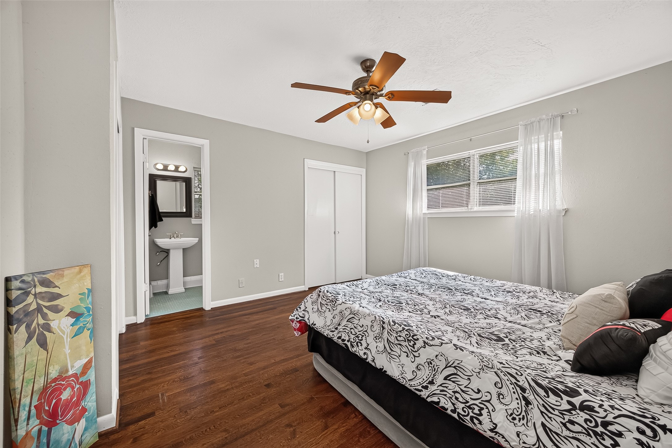 103 East Janisch Road Houston, TX 77022 - Photo 8 of 27 Primary bedroom featuring hardwood floors, a ceiling fan, and ample natural light. The EnSite bathroom offers convenience and privacy. Also offers dual closets.