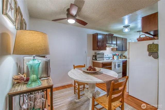 a kitchen with stainless steel appliances granite countertop a stove a refrigerator a sink a dining table and chairs with wooden floor