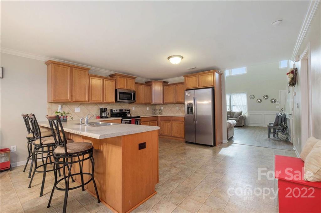 5846 Ringneck Road Charlotte, NC 28216 - Photo 7 of 28 a kitchen with stainless steel appliances granite countertop a refrigerator a stove a sink a dining table and chairs with wooden floor