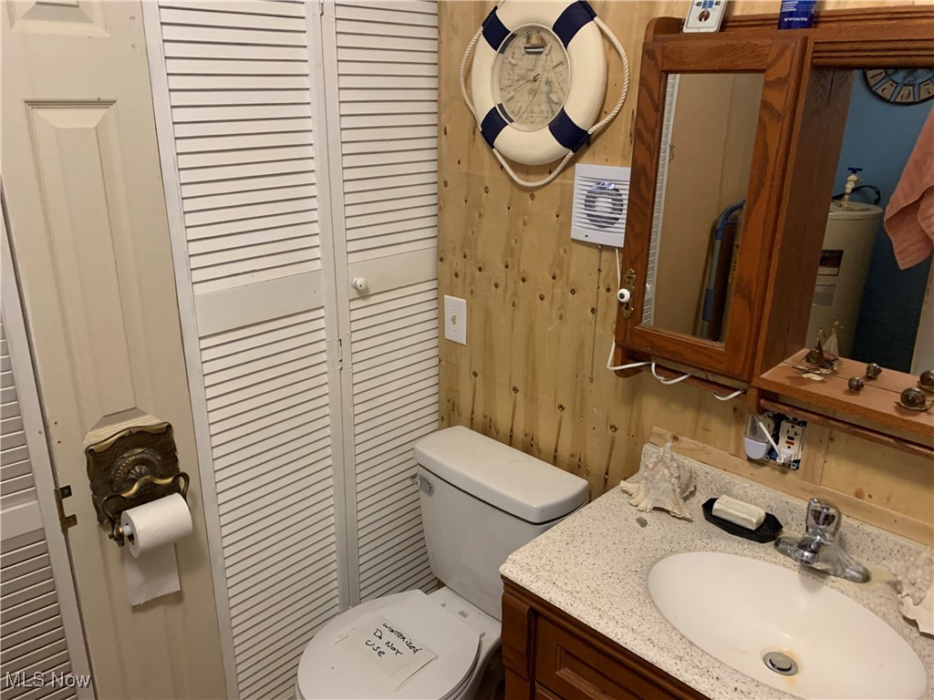 6431 Gibbs Road Andover, OH 44003 - Photo 8 of 20 Half bath with wood walls, a closet, vanity, and toilet