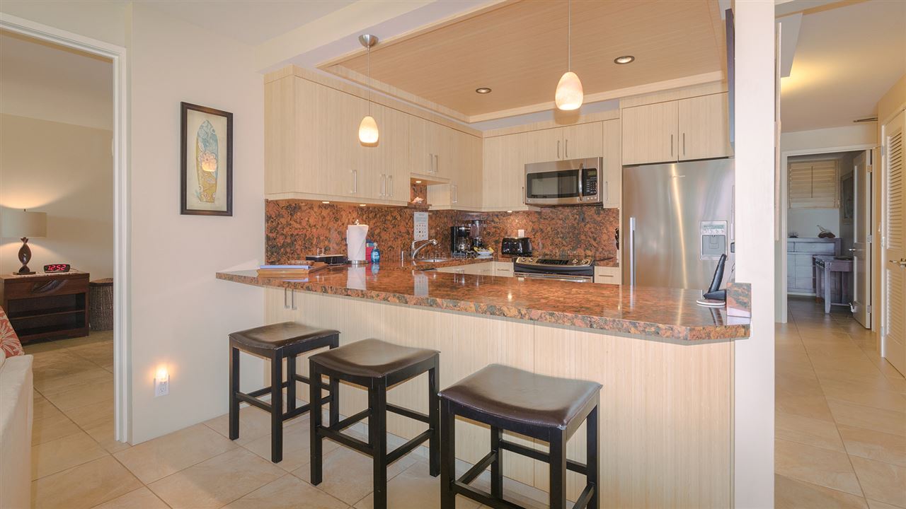 940 South Kihei Road, Unit B212 Kihei, HI 96753 - Photo 3 of 22 a kitchen with kitchen island granite countertop wooden cabinets and stainless steel appliances
