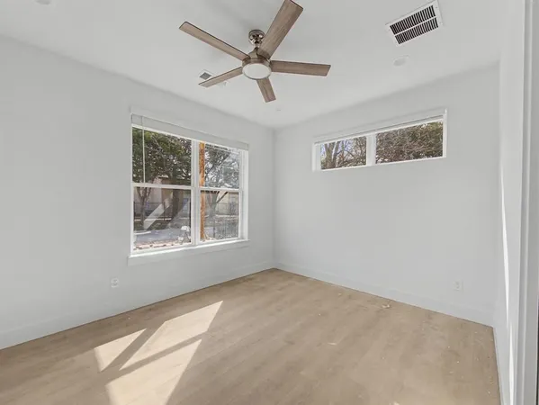 an empty room with wooden floor and windows