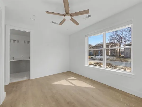 a view of empty room with wooden floor and fan