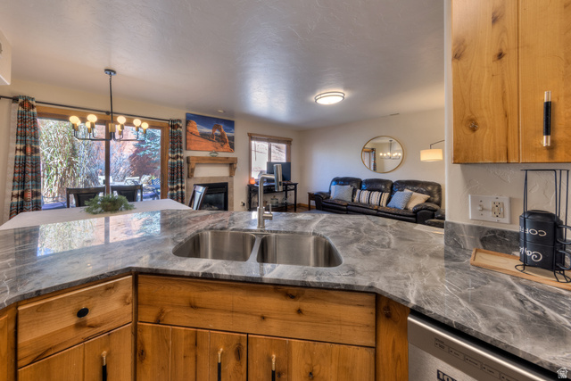 3461 Westwater Road, Unit 6 Moab, UT 84532 - Photo 33 of 33 Kitchen with wood finish cabinetry, open floor plan, a tiled fireplace, and a chandelier