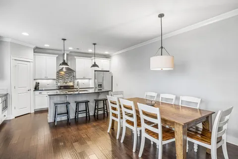 a view of a dining room and livingroom with furniture wooden floor a chandelier