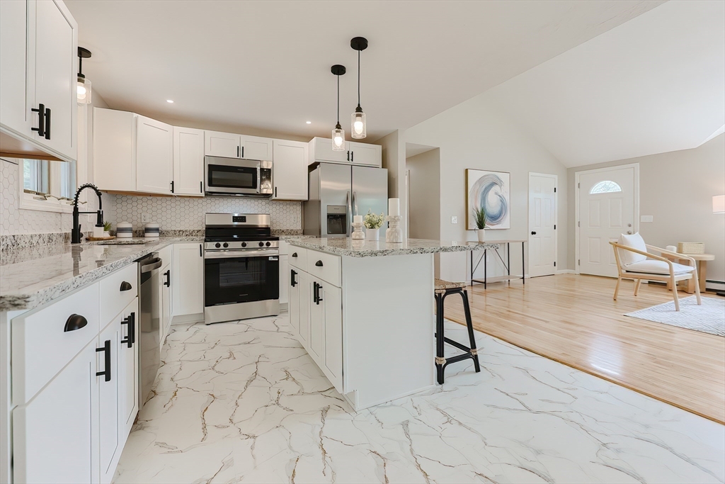 5 East Public Street Freetown, MA 02702 - Photo 16 of 41 a kitchen with stainless steel appliances granite countertop a stove top oven a sink a dining table and chairs with white wooden cabinets