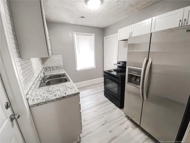 a kitchen with granite countertop refrigerator a sink a stove and island