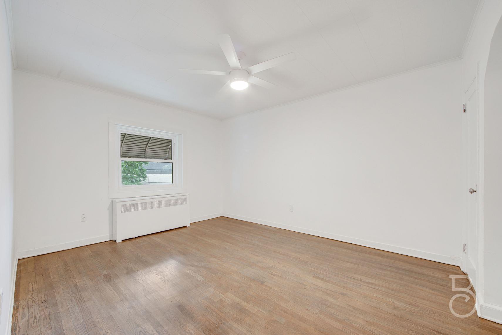 53-66 62nd Street Queens, NY 11378 - Photo 11 of 19 a view of an empty room with wooden floor and a window