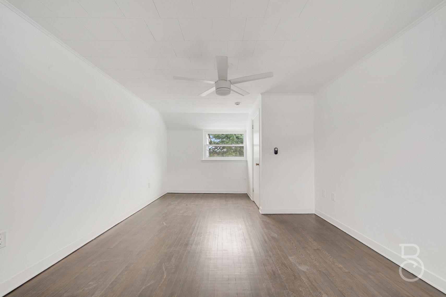 53-66 62nd Street Queens, NY 11378 - Photo 14 of 19 an empty room with wooden floor chandelier fan and windows