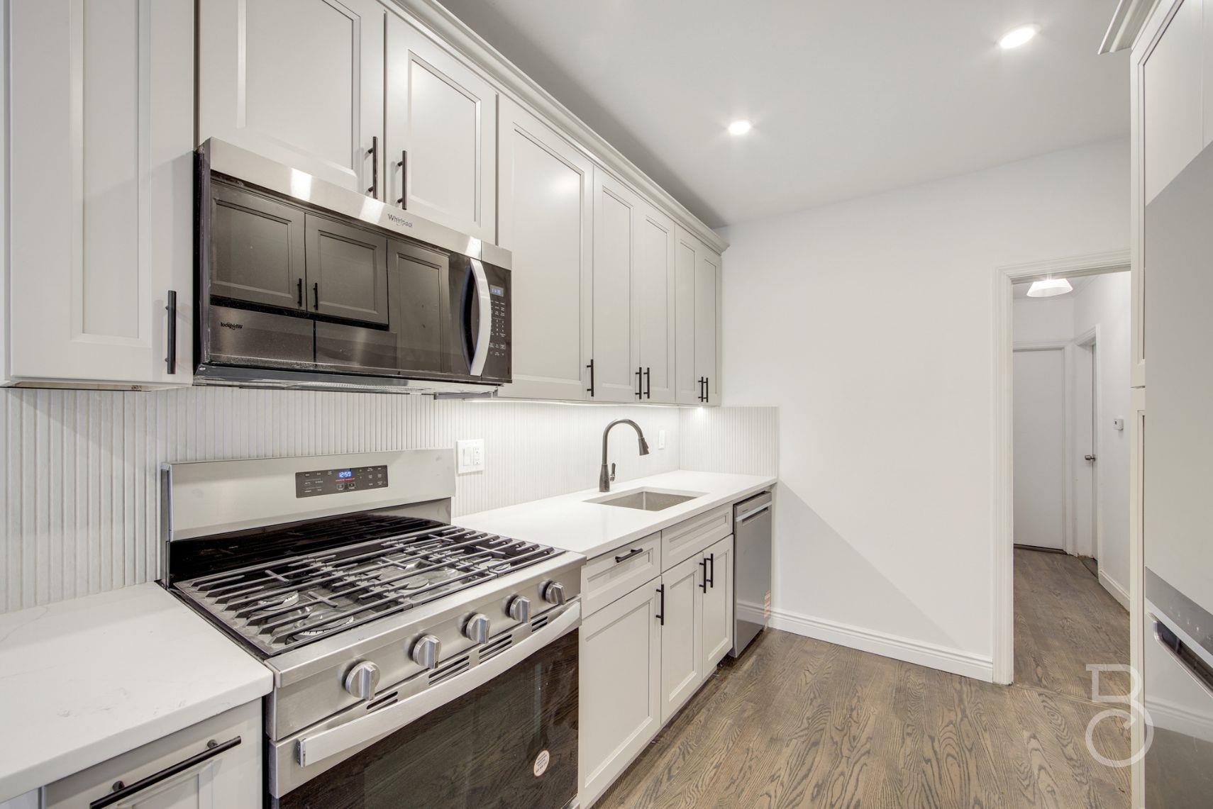53-66 62nd Street Queens, NY 11378 - Photo 2 of 19 a kitchen with stainless steel appliances a sink a stove and a microwave