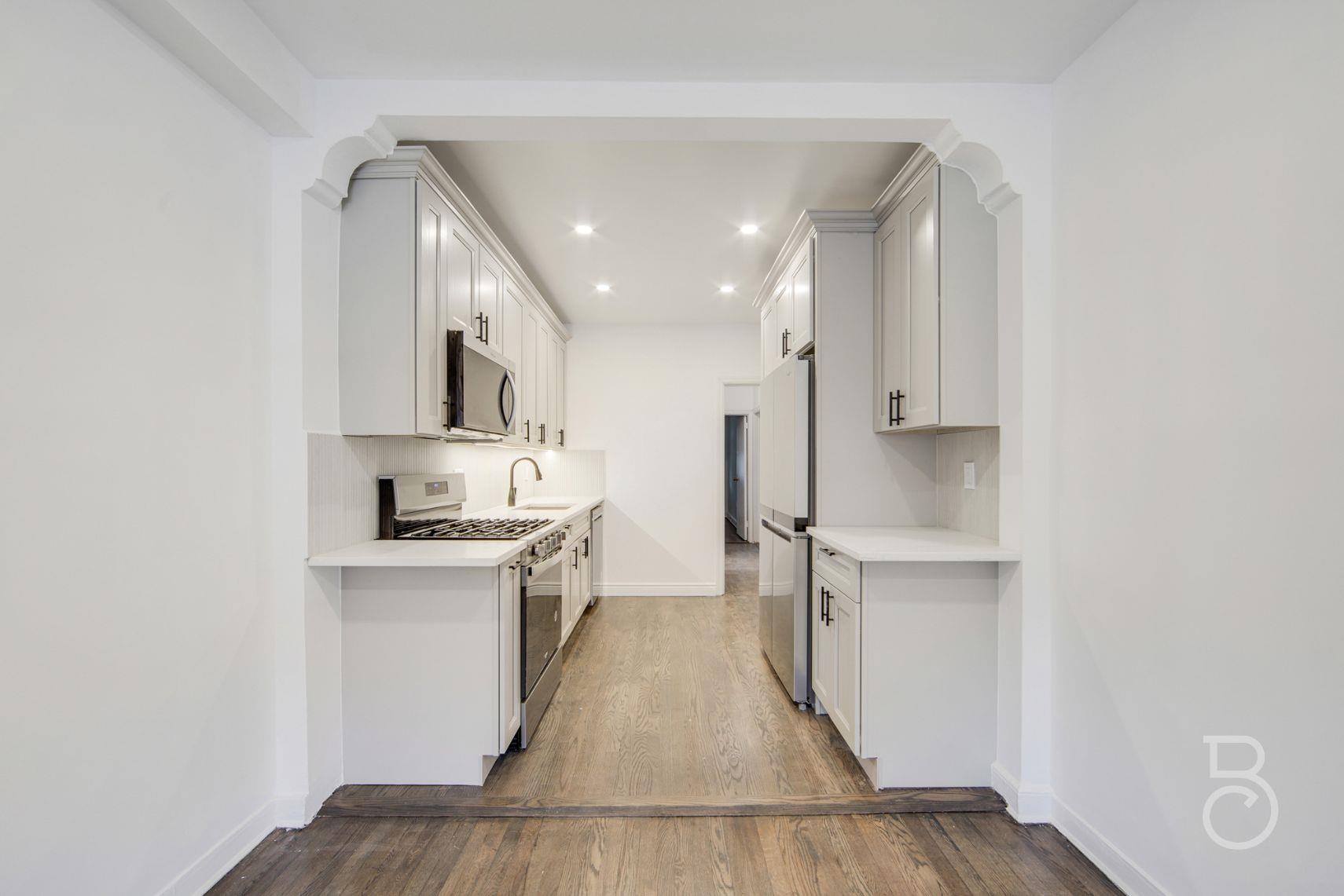 53-66 62nd Street Queens, NY 11378 - Photo 6 of 19 a kitchen with white cabinets and stainless steel appliances
