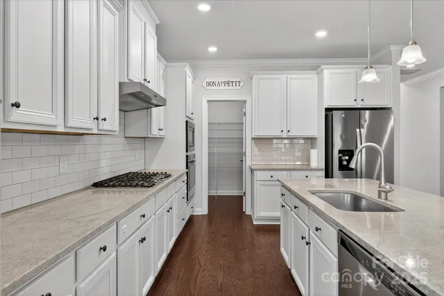 a kitchen with a sink a stove a refrigerator and white cabinets