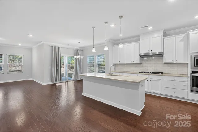 a large kitchen with granite countertop a large counter top stainless steel appliances and cabinets