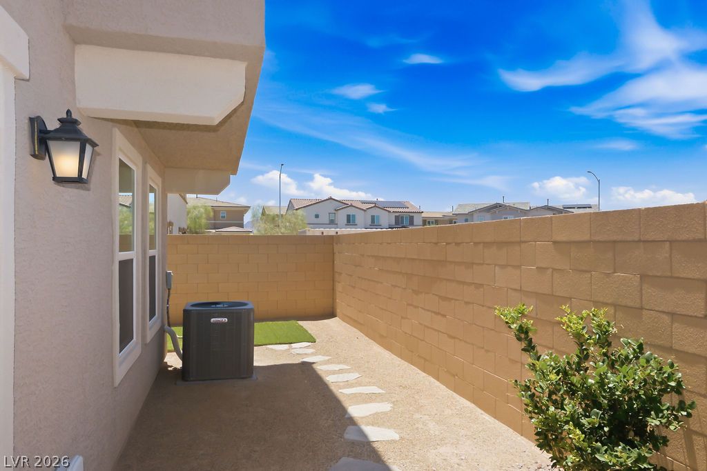 913 Cadence View Way Henderson, NV 89011 - Photo 39 of 46 A quaint patio area, enclosed by a privacy wall, offers a serene outdoor retreat under a clear blue sky.