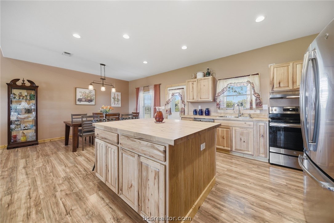 126 South Berlin Road Brenham, TX 77833 - Photo 12 of 30 a kitchen with stainless steel appliances granite countertop a stove top oven a sink a refrigerator and white cabinets with wooden floor