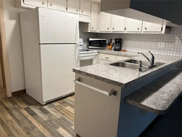 a white refrigerator freezer sitting inside of a kitchen with stainless steel appliances