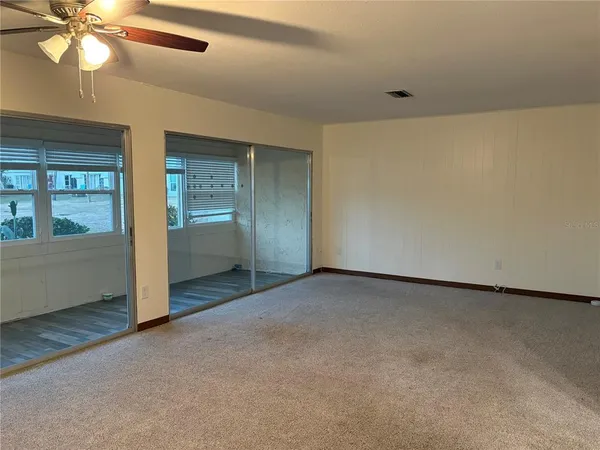 an empty room with windows and fan