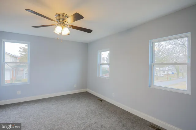 an empty room with windows and fan