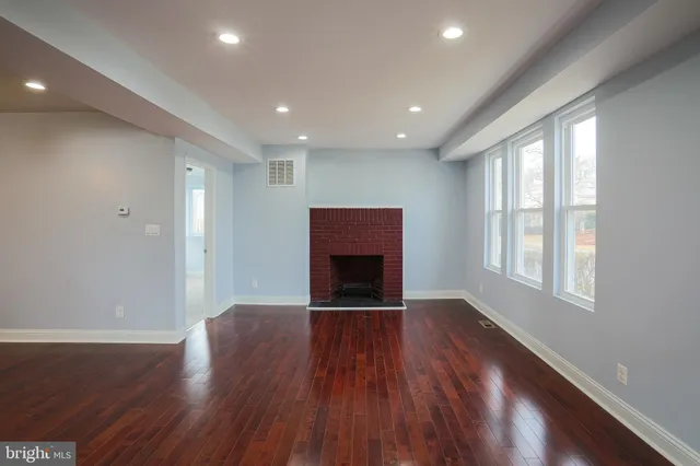 an empty room with wooden floor fireplace and windows