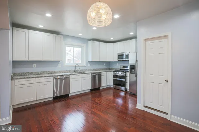 a kitchen with granite countertop stainless steel appliances cabinets a wooden floor and a window