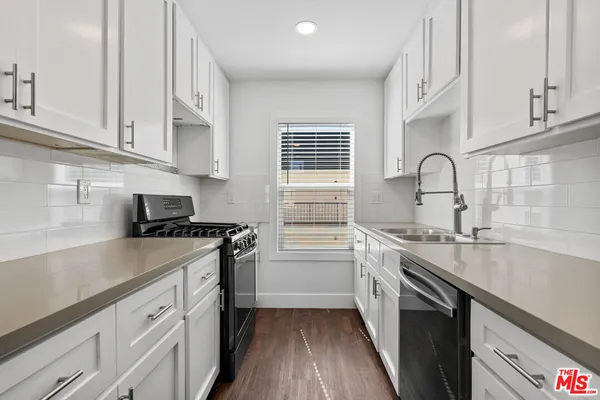 a kitchen with stainless steel appliances granite countertop a sink stove refrigerator and cabinets