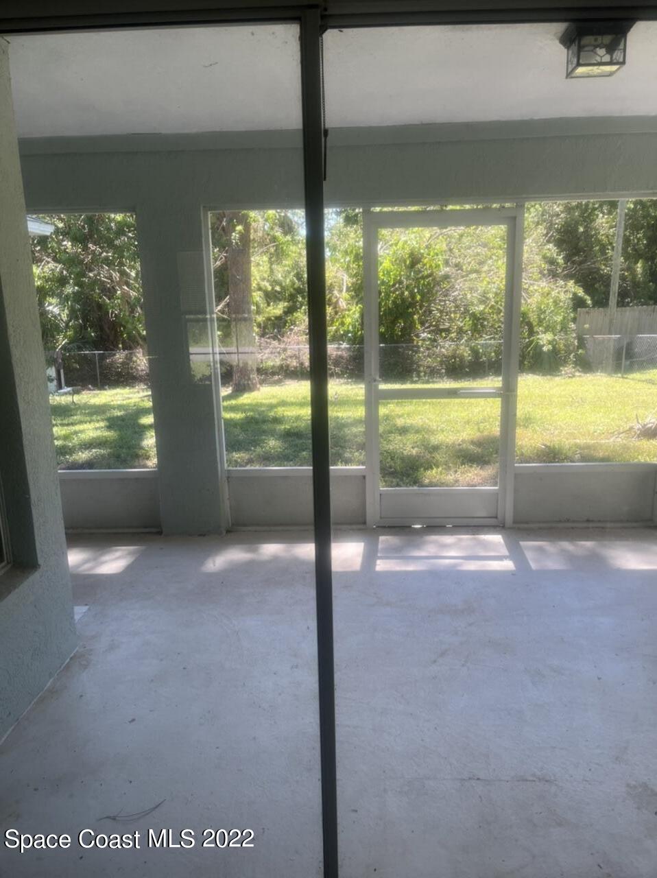 544 Plumbago Road Northwest Palm Bay, FL 32907 - Photo 16 of 16 a view of an empty room with a floor to ceiling window and a tree