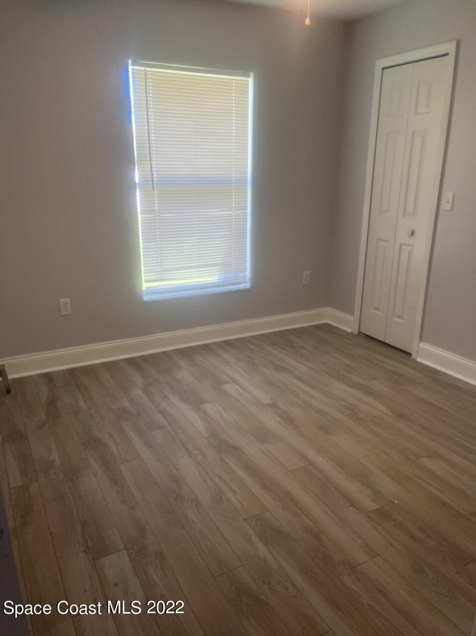 544 Plumbago Road Northwest Palm Bay, FL 32907 - Photo 7 of 16 an empty room with wooden floor and windows