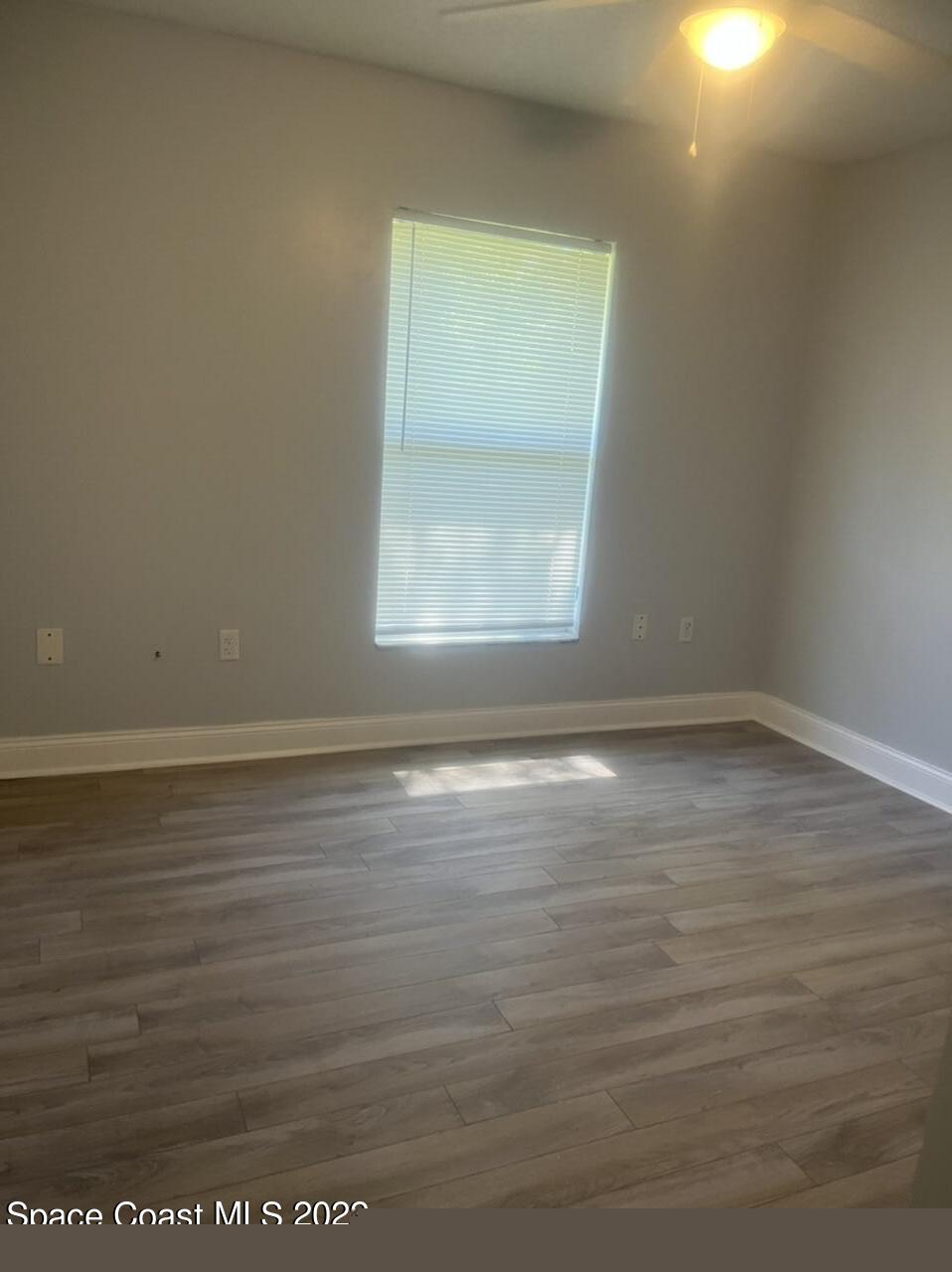 544 Plumbago Road Northwest Palm Bay, FL 32907 - Photo 8 of 16 a view of an empty room with wooden floor and a window