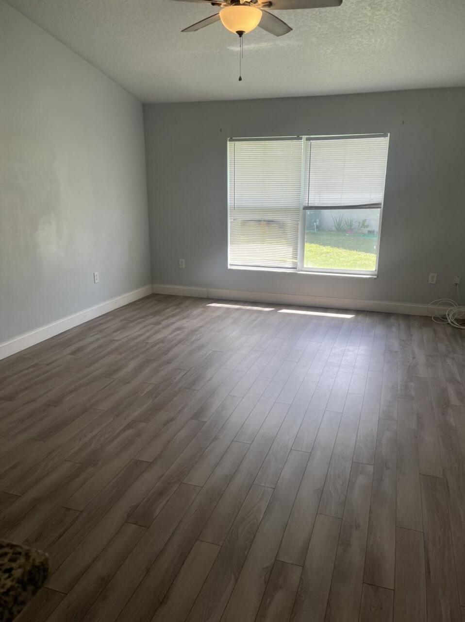 544 Plumbago Road Northwest Palm Bay, FL 32907 - Photo 10 of 16 an empty room with wooden floor and windows