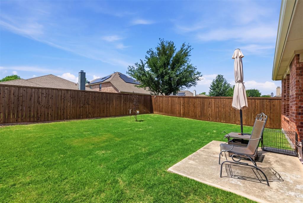 5491 Exeter Drive Prosper, TX 75078 - Photo 18 of 20 a view of a backyard with table and chairs potted plants and wooden fence