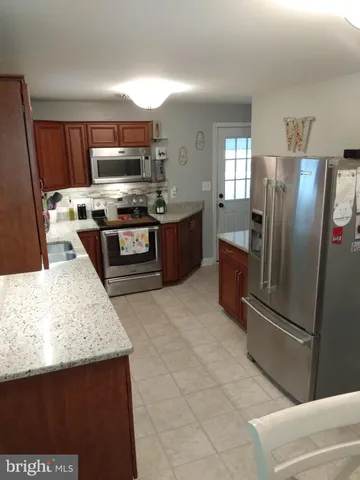 a kitchen with stainless steel appliances granite countertop a refrigerator a stove and a sink