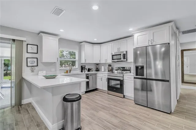 a kitchen with a refrigerator a sink dishwasher a stove and white cabinets with wooden floor