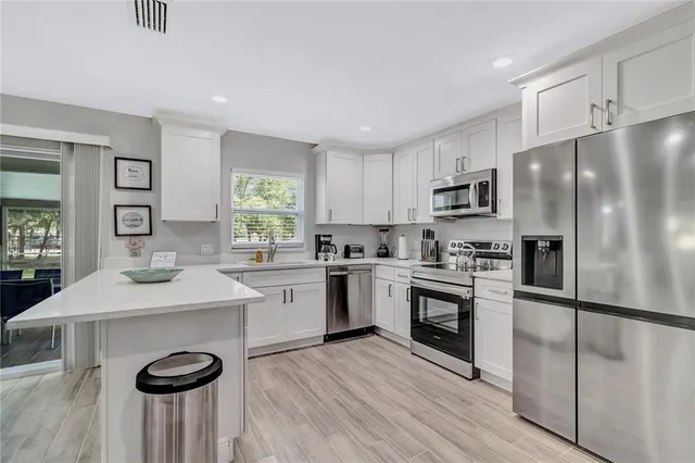 a kitchen with granite countertop a center island stainless steel appliances cabinets and a window
