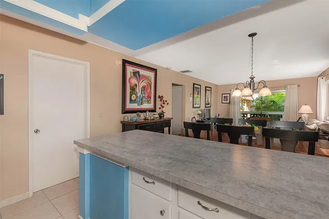 a kitchen with stainless steel appliances granite countertop a refrigerator a sink dishwasher a dining table and chairs with wooden floor