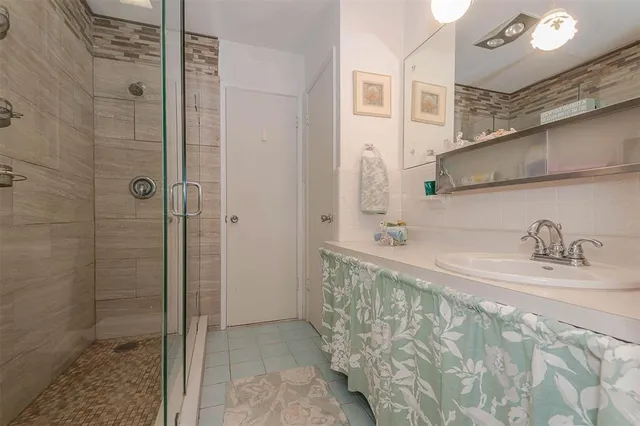 a bathroom with a granite countertop sink a mirror and shower