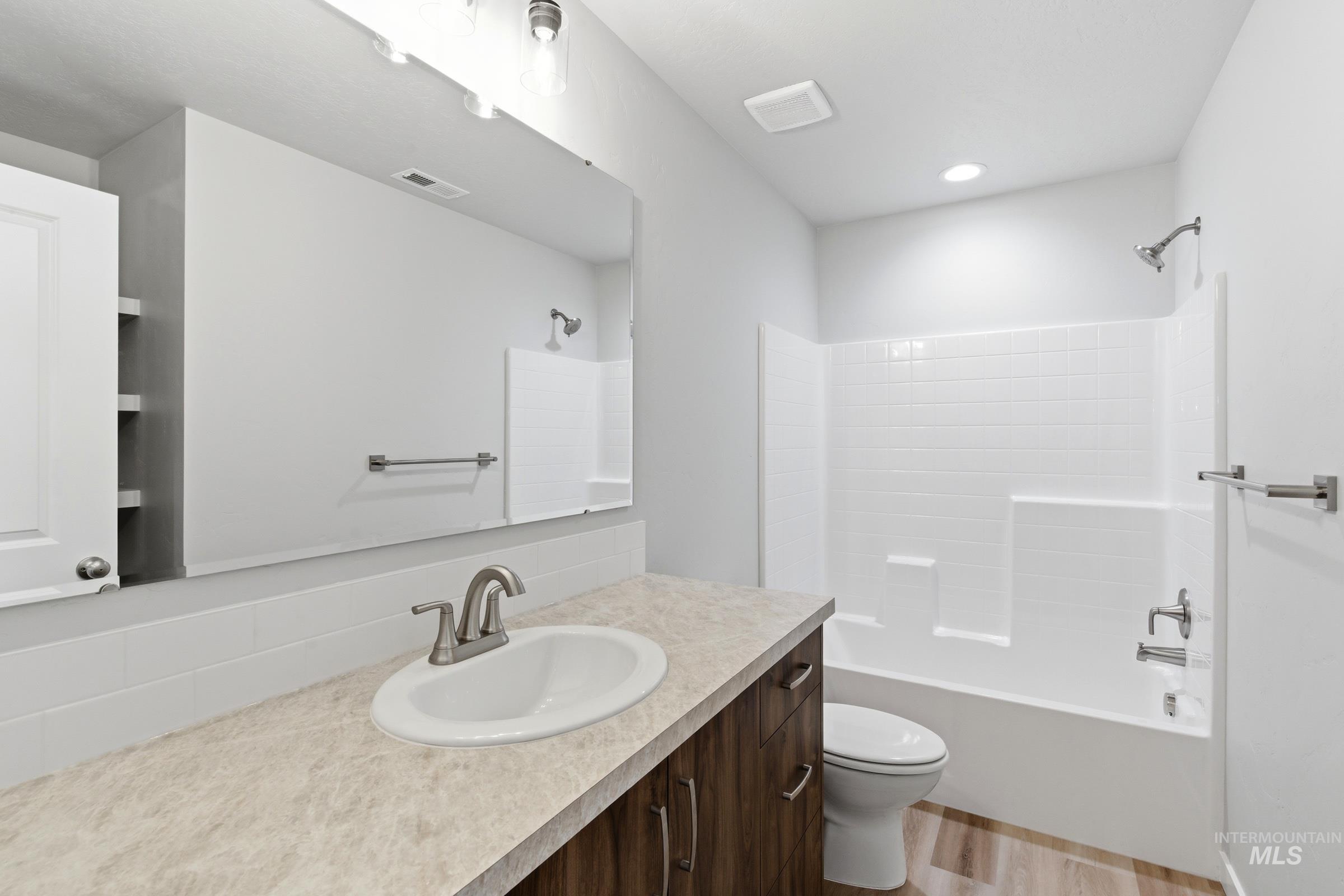 13709 Redway Court Caldwell, ID 83607 - Photo 20 of 28 Bathroom featuring a wood-finish vanity with an integrated sink, a large wall mirror, and a full bathtub with a subway tile surround