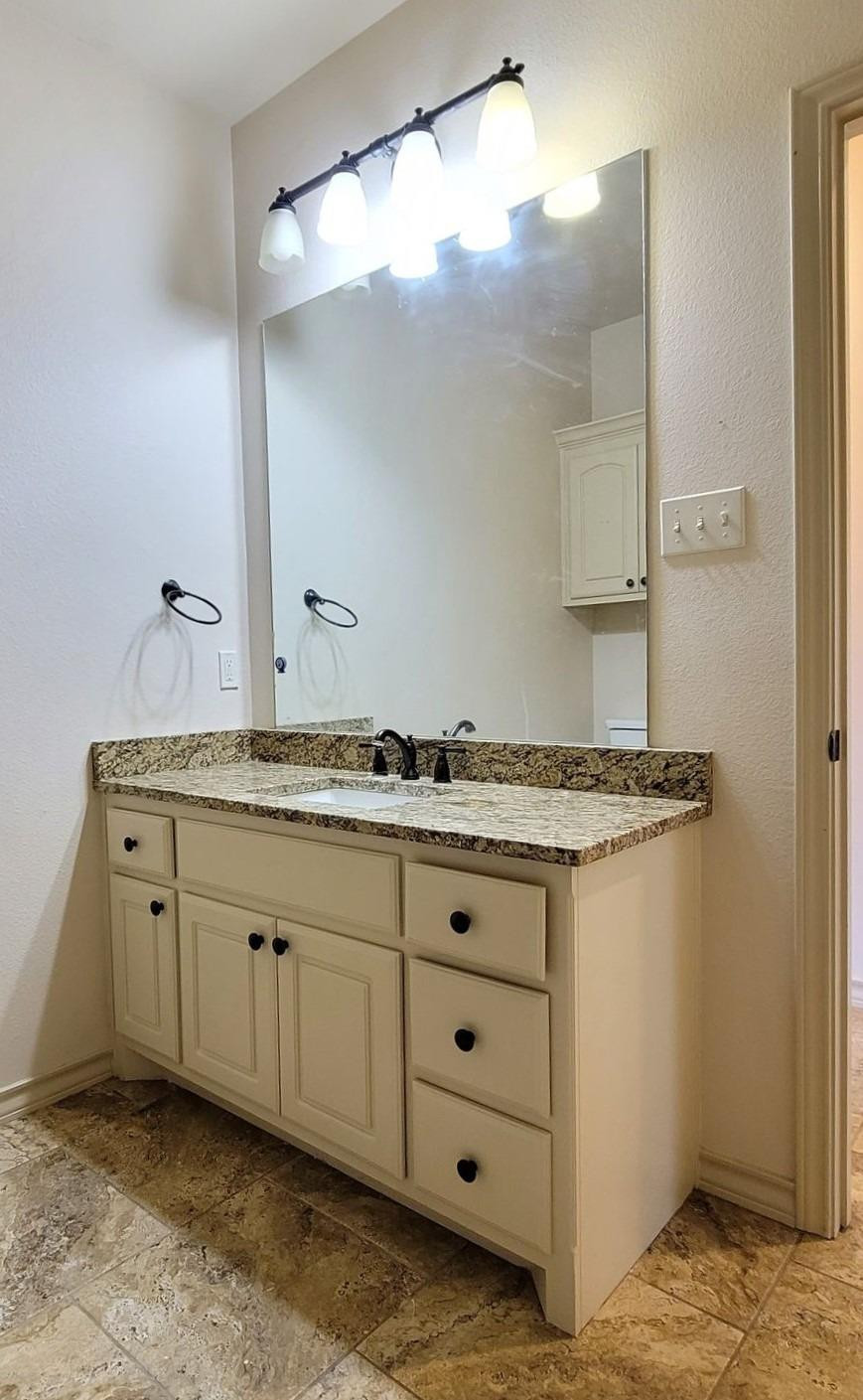 5234 Kemper Street Lubbock, TX 79416 - Photo 26 of 28 a bathroom with a granite countertop sink and a mirror