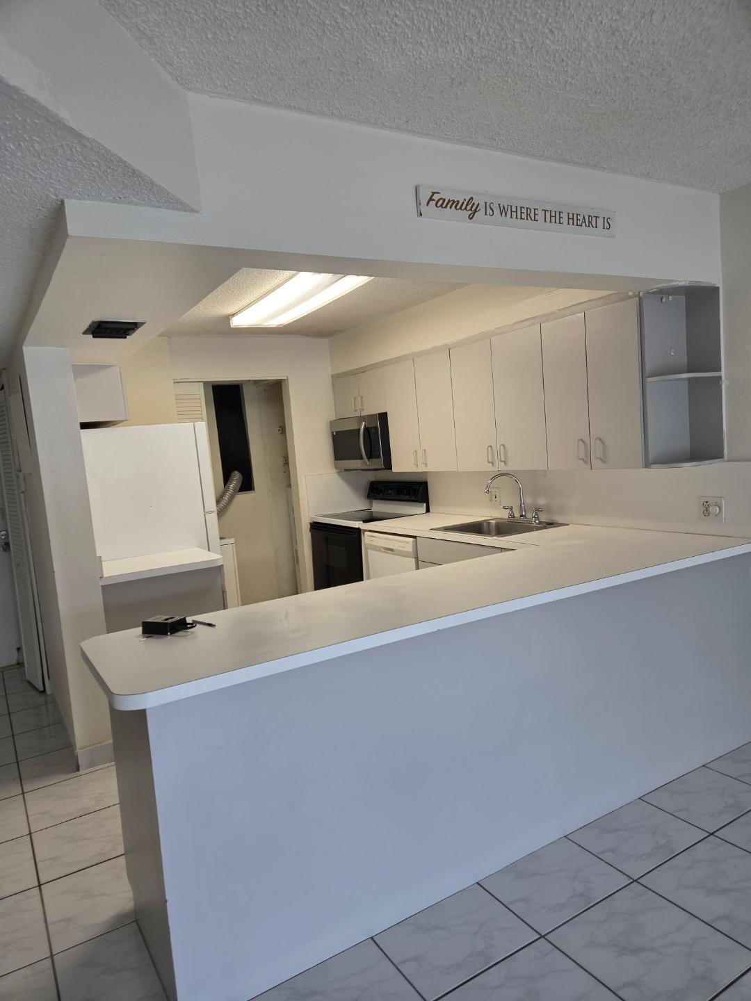 a kitchen with stainless steel appliances a sink a stove a microwave a refrigerator a sink and white cabinets