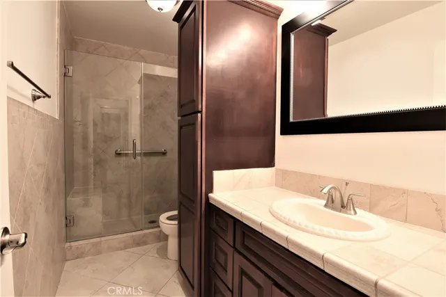 a bathroom with a granite countertop sink a toilet and shower