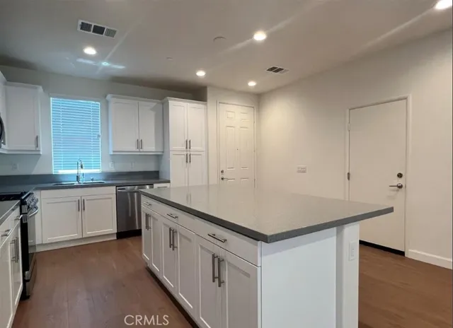 a kitchen that has a lot of white cabinets and wooden floor