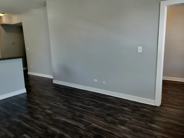 a view of an empty room with wooden floor and a sink