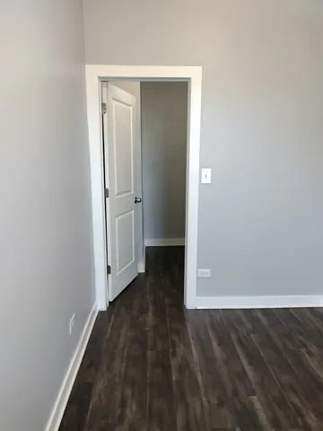 an empty room with wooden floor and entrance