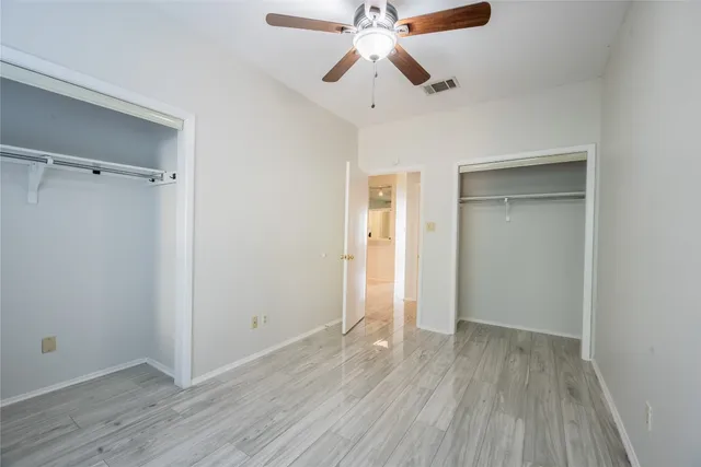 an empty room with wooden floor a ceiling fan and closet