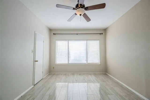 an empty room with wooden floor ceiling fan and windows