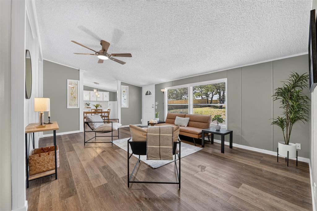 449 Big Salty Lane Springtown, TX 76082 - Photo 4 of 25 Spacious living area featuring wood-finish flooring, light gray wall paneling, and a ceiling fan with integrated lighting