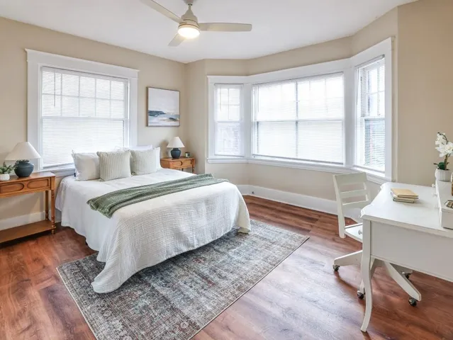 a bedroom with a bed wooden floor and a large window