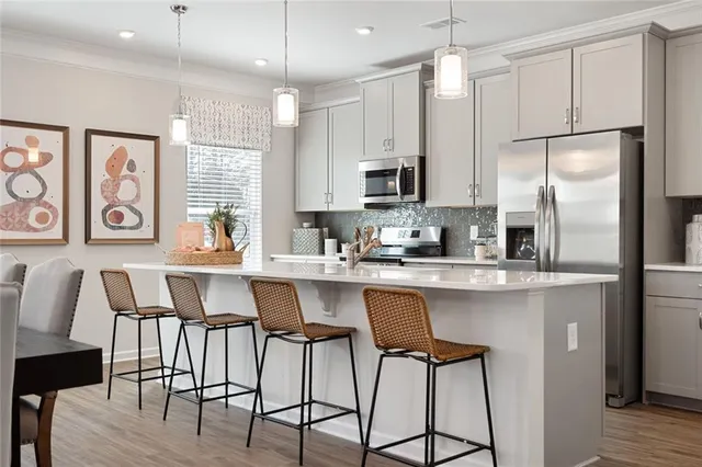 a kitchen with stainless steel appliances kitchen island a white table chairs and a sink